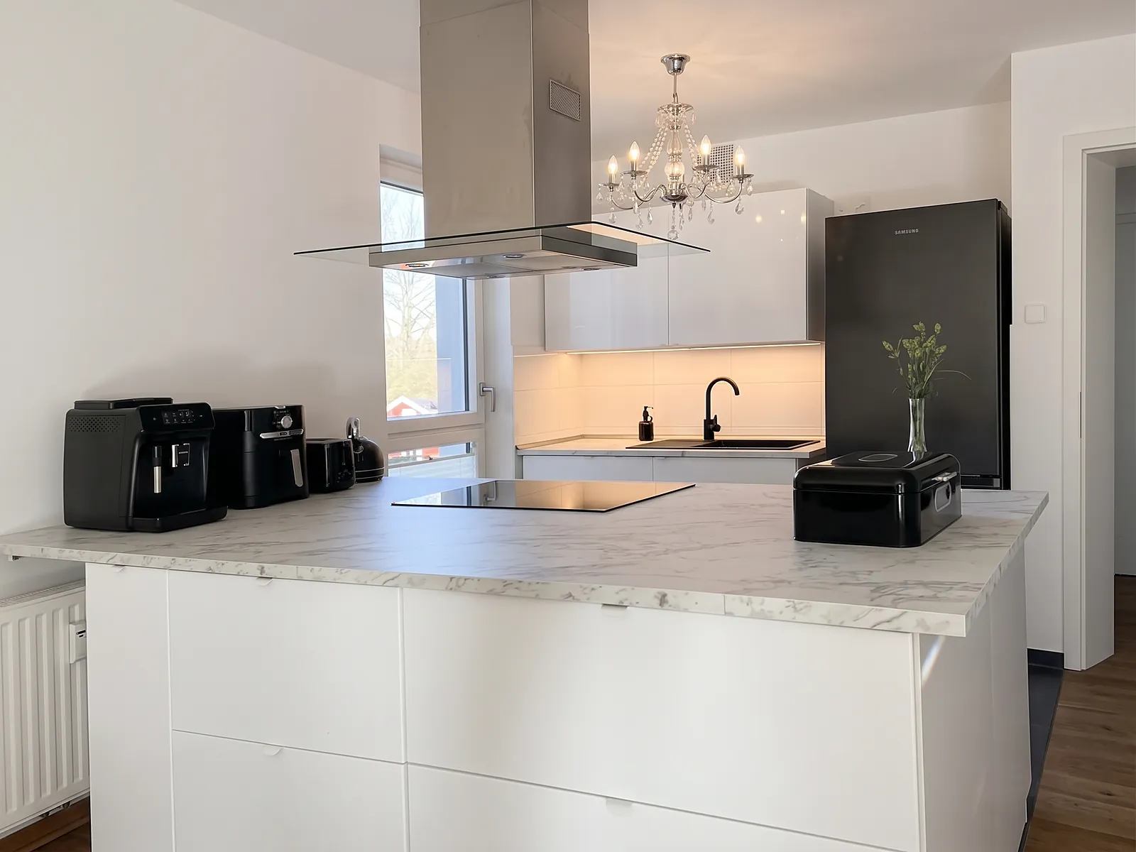 Weiße Kücheninsel mit Arbeitsplatte in Marmoroptik und Induktionskochfeld