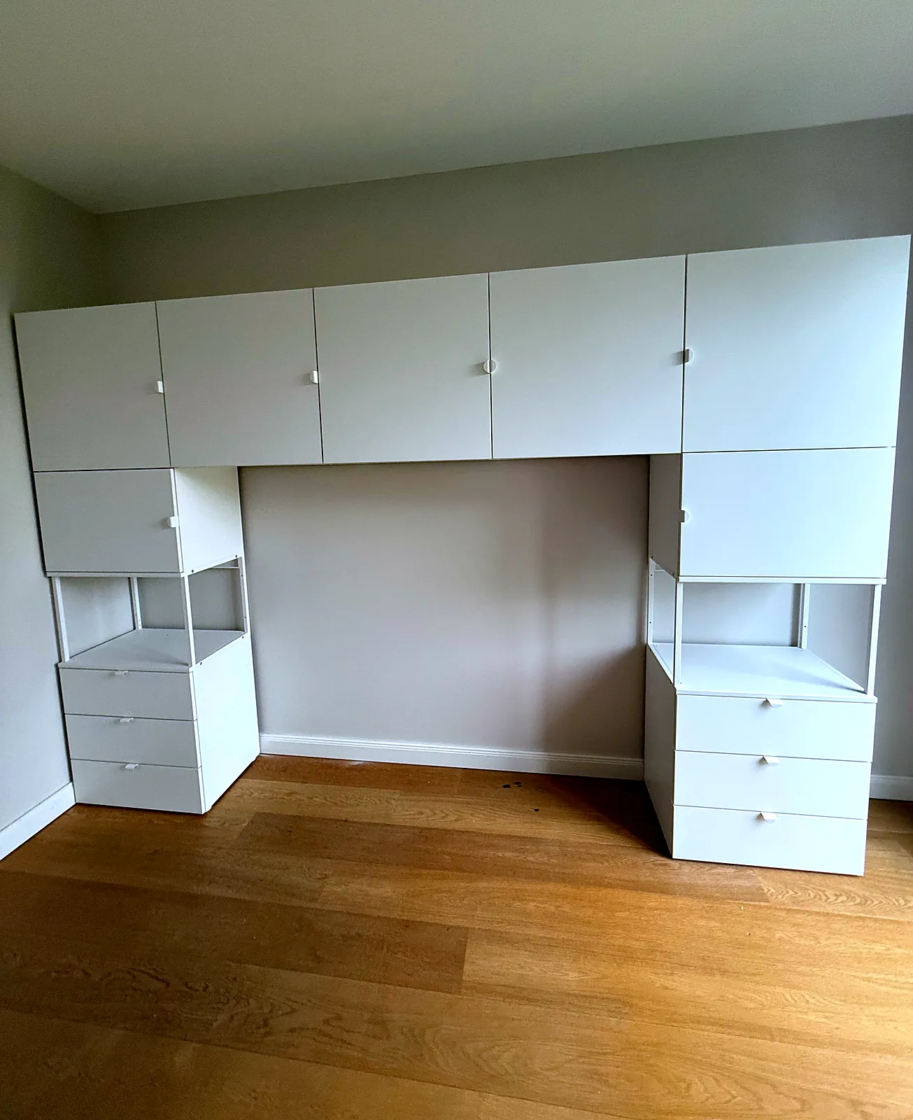 Weiße Hängeschränke rund um den Platz für ein Bett montiert